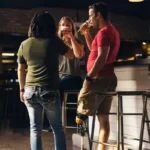 A man drinking at a bar with friends whlst having a disability