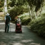 Two disabled older people travelling through a park