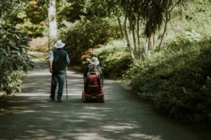 Two disabled older people travelling through a park