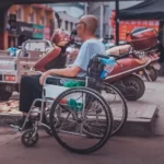A disable man sat in a wheelcahir facing out into the road