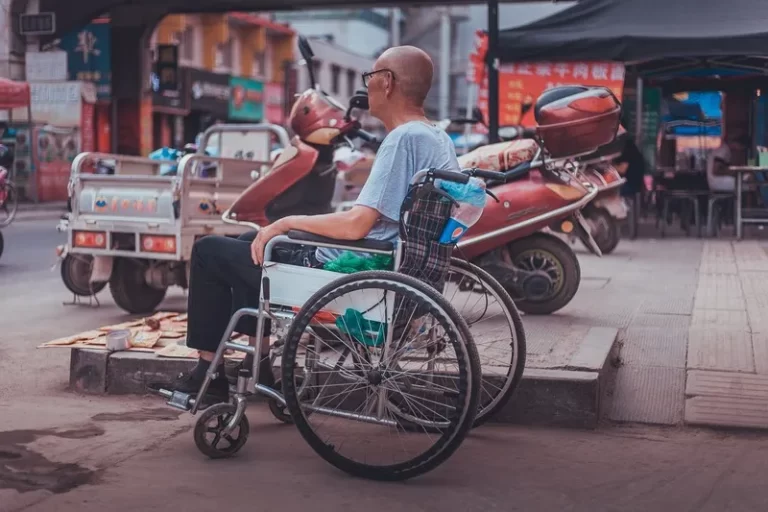A disable man sat in a wheelcahir facing out into the road