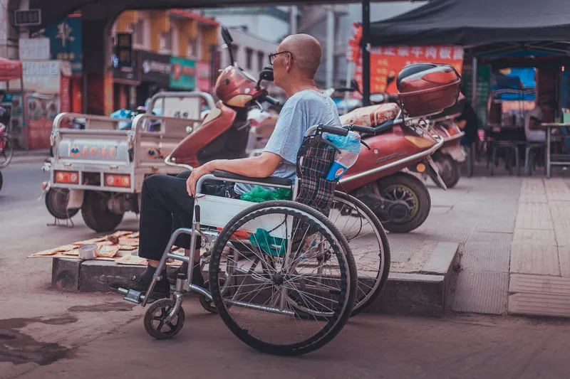 A disable man sat in a wheelcahir facing out into the road