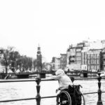 a disabled person alone by the river wearing a hoody and sitting in a wheelchair