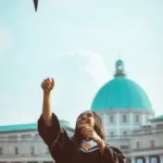 A university graduate throwing their mortar board into the air on a sunny day