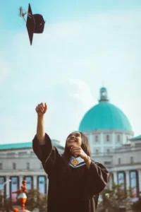 A university graduate throwing their mortar board into the air on a sunny day