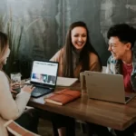 three people sat around a laptop learning education
