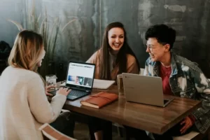 three people sat around a laptop learning education
