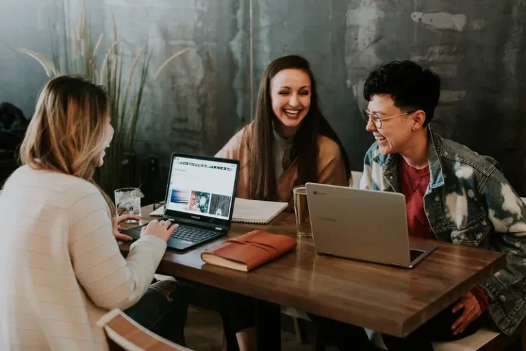 three people sat around a laptop learning education