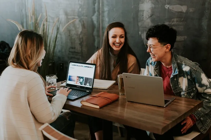 three people sat around a laptop learning education