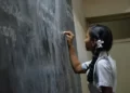 A young girl writing on a chalk board grammar school