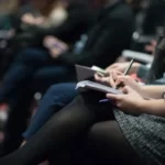 A row of students with writing materials on their laps