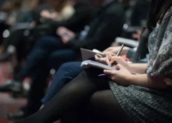 A row of students with writing materials on their laps