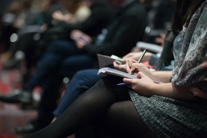 A row of students with writing materials on their laps