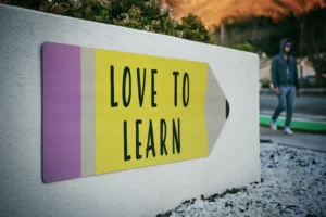 A white wall with a mural in the shape of a pencil and reads 'love to learn'