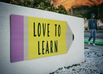 A white wall with a mural in the shape of a pencil and reads 'love to learn'