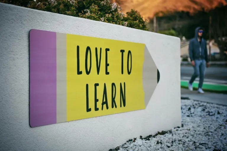 A white wall with a mural in the shape of a pencil and reads 'love to learn'