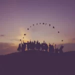 A line of graduates at sunset throwing their mortar boards in tair