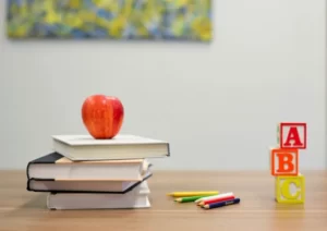 a stack of education books and an apple on a table