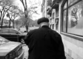 black and white image of the back of a man walking down the street