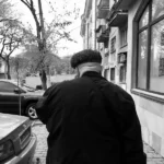 black and white image of the back of a man walking down the street