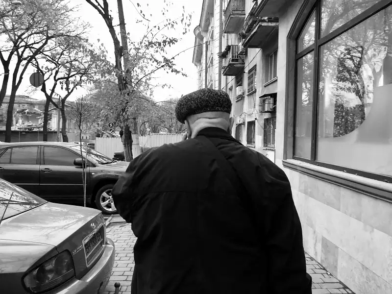 black and white image of the back of a man walking down the street