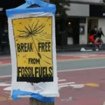 A poster stating 'break free from fossil fuels' attached to a lamp post.