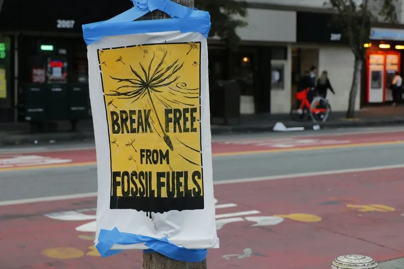 A poster stating 'break free from fossil fuels' attached to a lamp post.