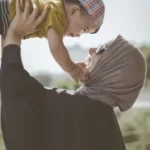 A mother and young son. the mother is holding the son in the air