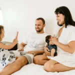 A cohabiting family with two adults and one child sat on a bed
