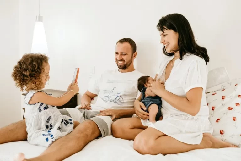 A cohabiting family with two adults and one child sat on a bed