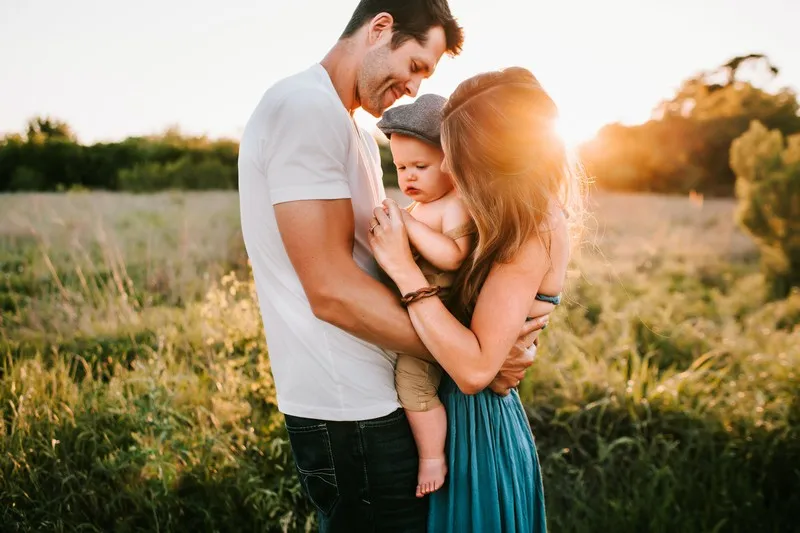 A man and woman holding a baby at sunset