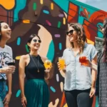 4 female friends smiling in front of a colourful mural