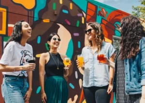 4 female friends smiling in front of a colourful mural