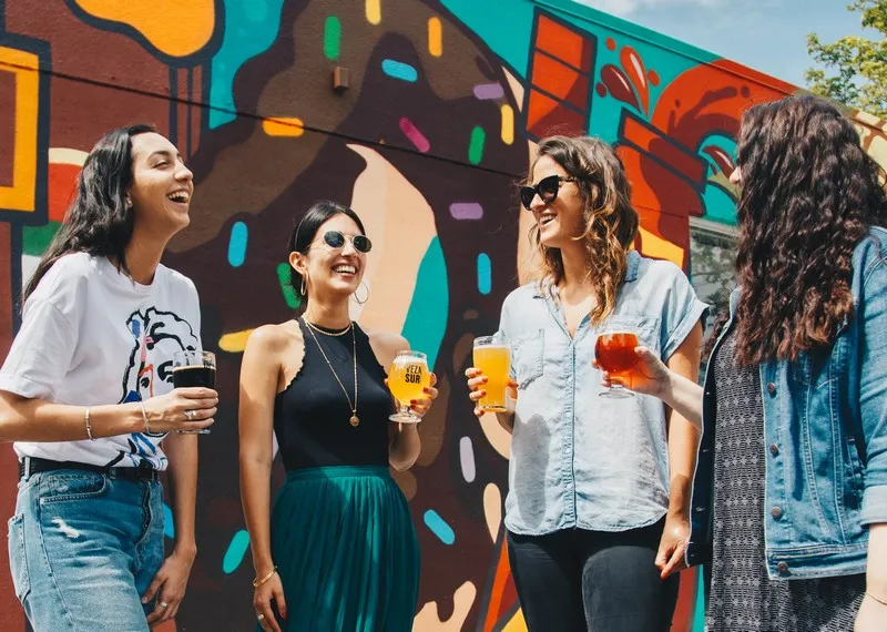 4 female friends smiling in front of a colourful mural