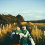 Two women walking through a field with their arms around each other