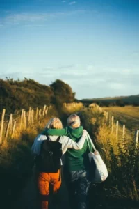 Two women walking through a field with their arms around each other