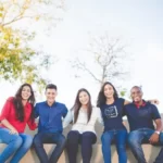A group of friends sat on a wall on a sunny day expressing solidarity