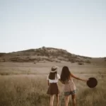 Two girls walking across dull fields