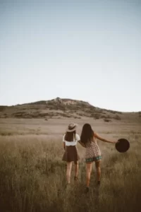 Two girls walking across dull fields