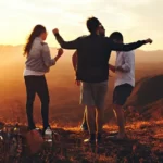 A group of friends on a mountaintop at sunset