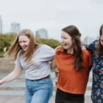A group of three female friends walking arm in arm