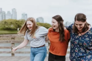 A group of three female friends walking arm in arm