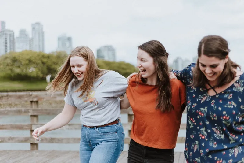 A group of three female friends walking arm in arm