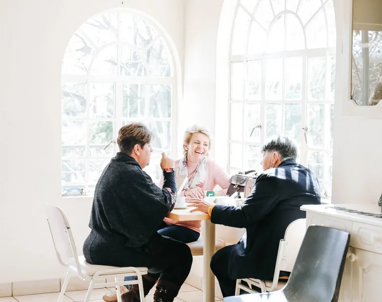 Some friends ahving a coffee in a cafe in front of bright windows on a sunny day