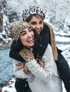 Two females hugging and laughing in the snow