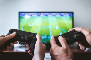 Two controllers in front of a TV playing a football game