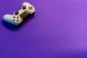 A PS4 controller against a purple hued background.