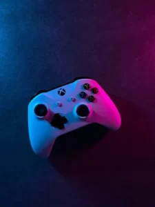 A white xbox controller under purple and pink lighting