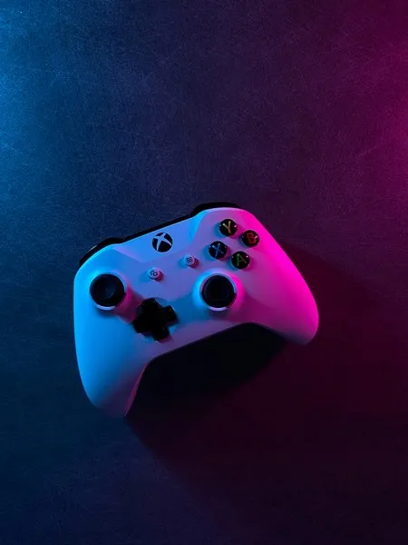 A white xbox controller under purple and pink lighting
