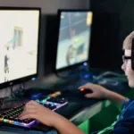 A boy playing video games in the dark wearing headphones